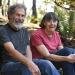 An older man and woman sitting on stone steps smiling.